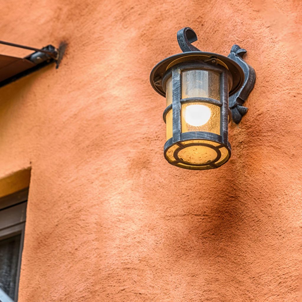 Dark brown outside lighting fixture against a stone wall.; Shutterstock ID 527933680; Job (TFH, TOH, RD, BNB, CWM, CM): Taste of Home