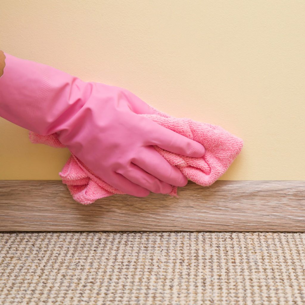 Hand in rubber protective glove with microfiber cloth cleaning baseboard on the floor from dust at the wall. Early spring cleaning or regular clean up. Maid cleans house.; Shutterstock ID 687988345; Job (TFH, TOH, RD, BNB, CWM, CM): Taste of Home