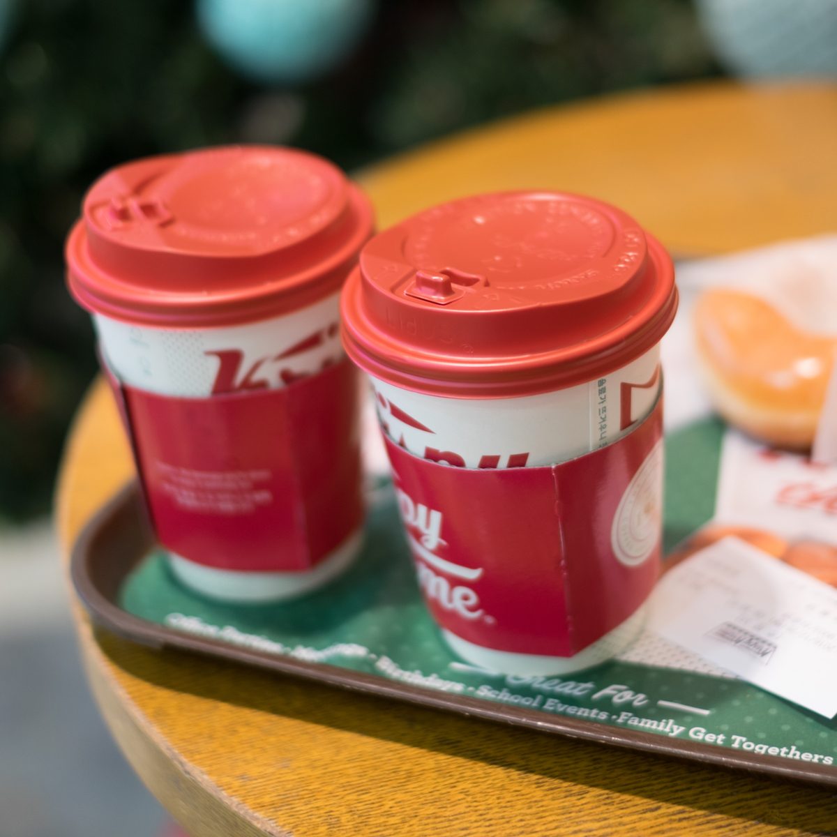 take away hot coffee beverage served in a tall red Christmas designed cup with sweet krispy kreme donut