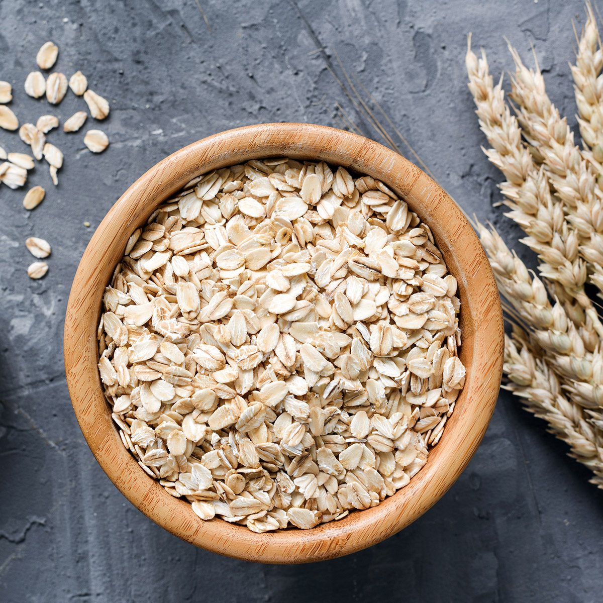 Oats or rounded oats in a corner in a wooden bowl and stone background.