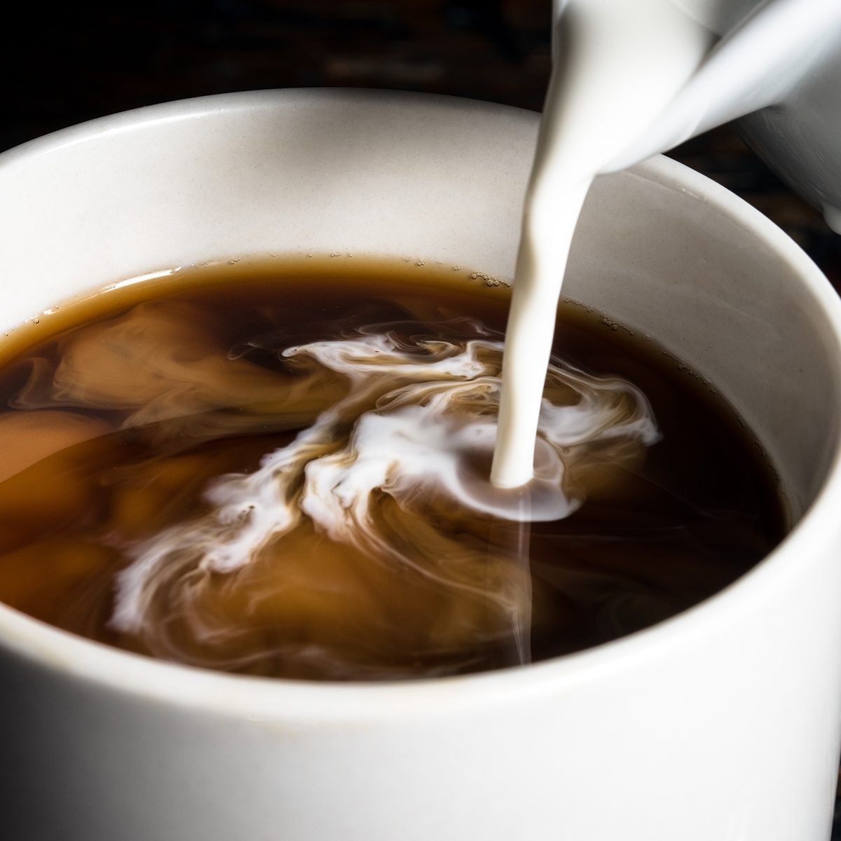 Pouring Cream into a Cup of Coffee