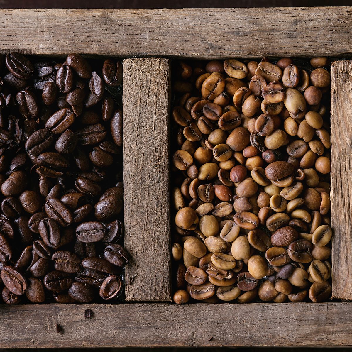 Food background with green and brown decaf unroasted and black roasted coffee beans in old wooden box