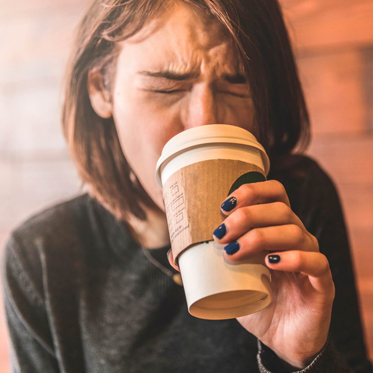 Woman burning her tongue while drinking coffee