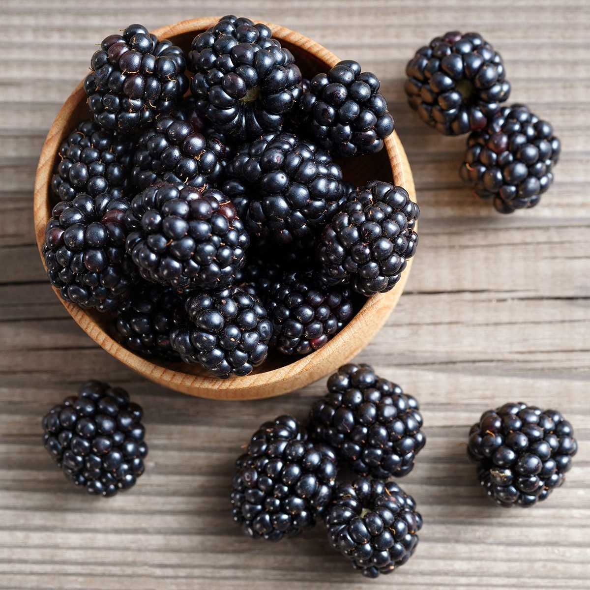 Deluxe blackberries in bowl on wooden background. 