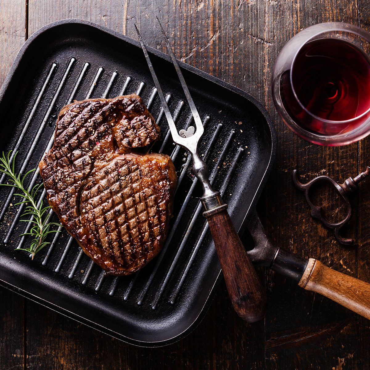 Grilled Black Angus Steak Ribeye on grill iron pan on wooden background with wine
