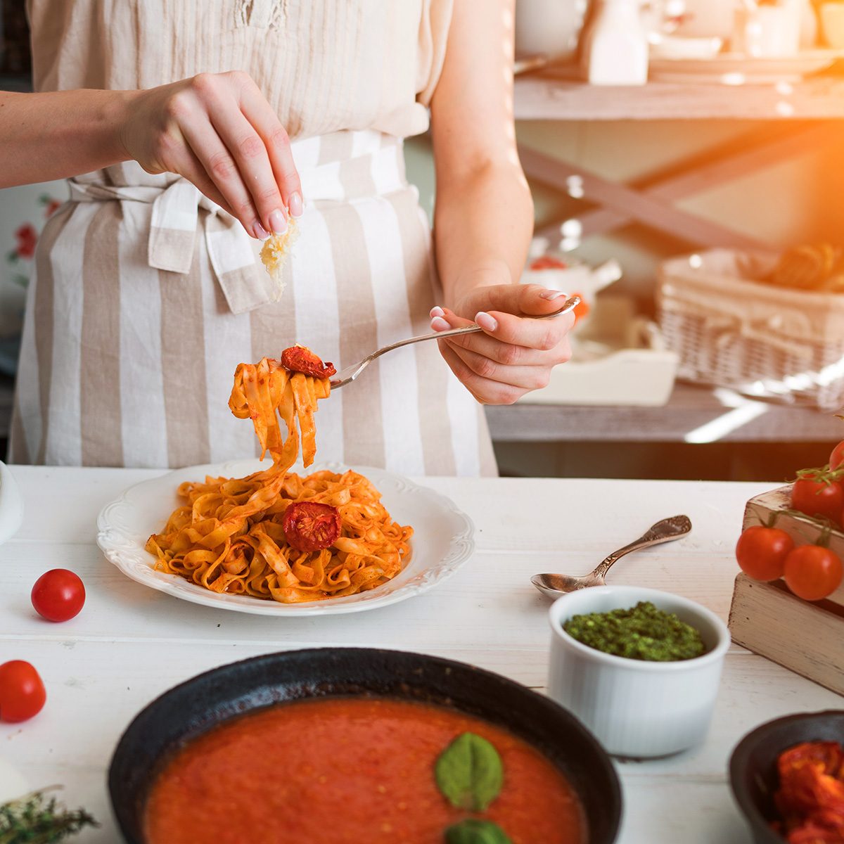 Italian style pasta dinner. Pasta with tomato and basil in plate on the wooden rustic table and ingredients for cooking. Chef hands preparing delicious pasta with tomato sous. Homemade food.; Shutterstock ID 1084753496; Job (TFH, TOH, RD, BNB, CWM, CM): Taste of Home