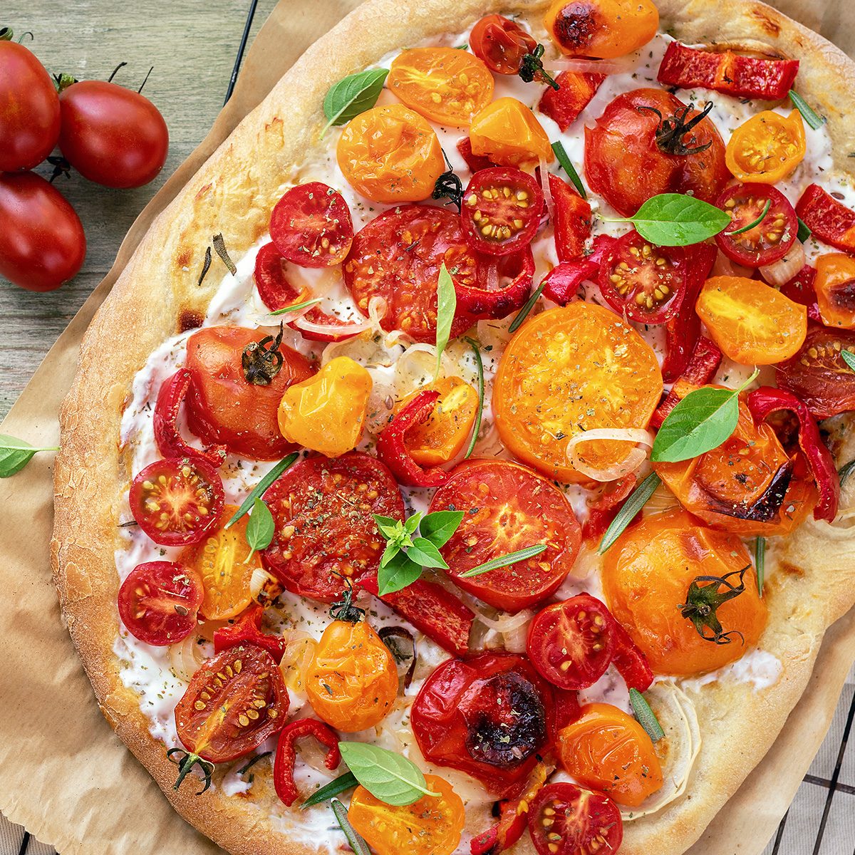 Oval pizza with yellow and red cherry tomatoes, ricotta cheese and basil on a wooden table.; Shutterstock ID 1193446483; Job (TFH, TOH, RD, BNB, CWM, CM): Taste of Home