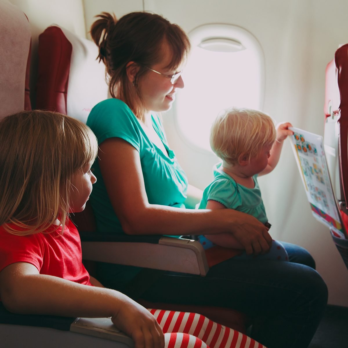 family travel by plane- mother wtih two kids in flight; Shutterstock ID 728235709