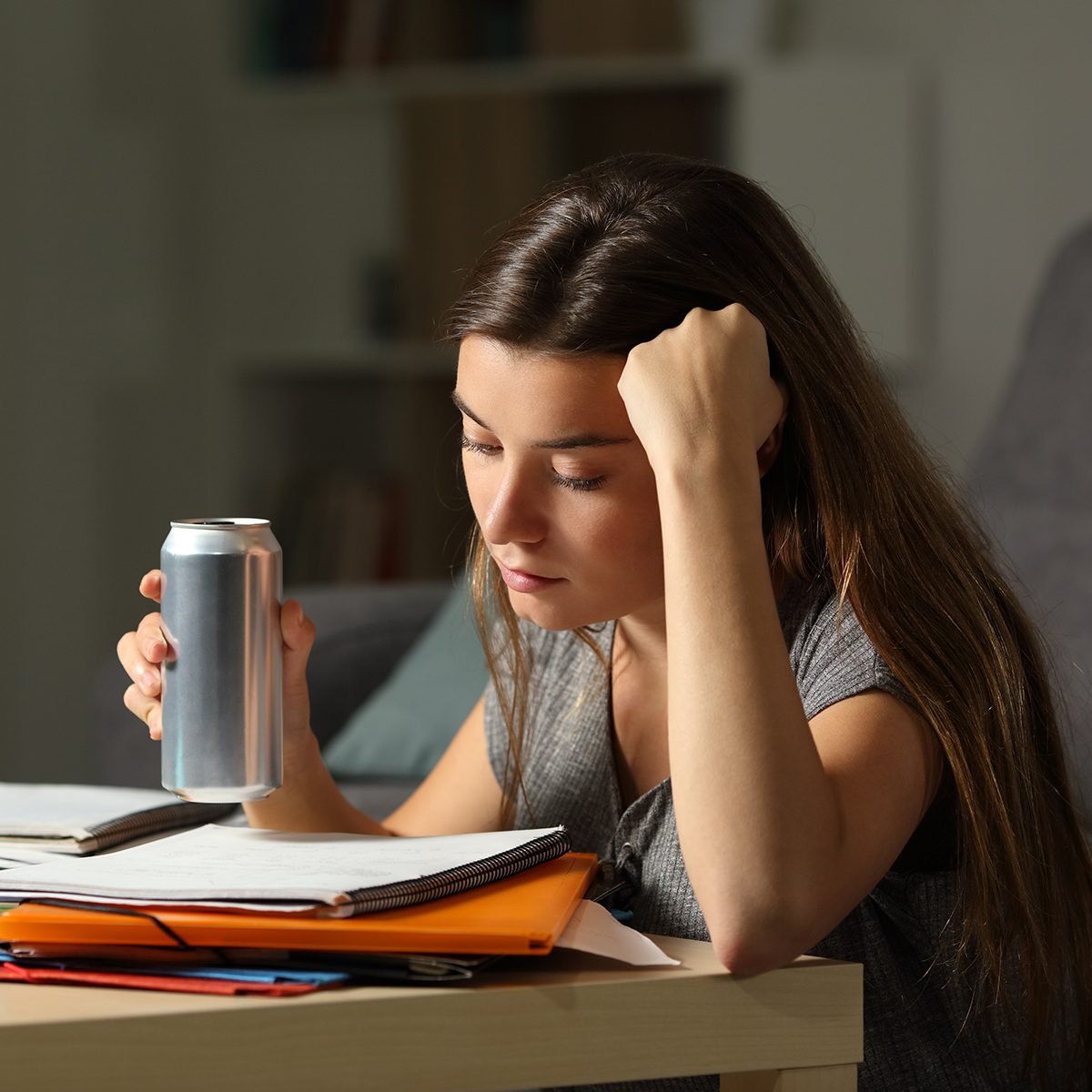 Student preparing exam memorizing notes holding and energy drink in the night at home