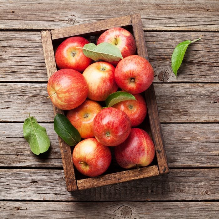 Ripe red apples in wooden box.