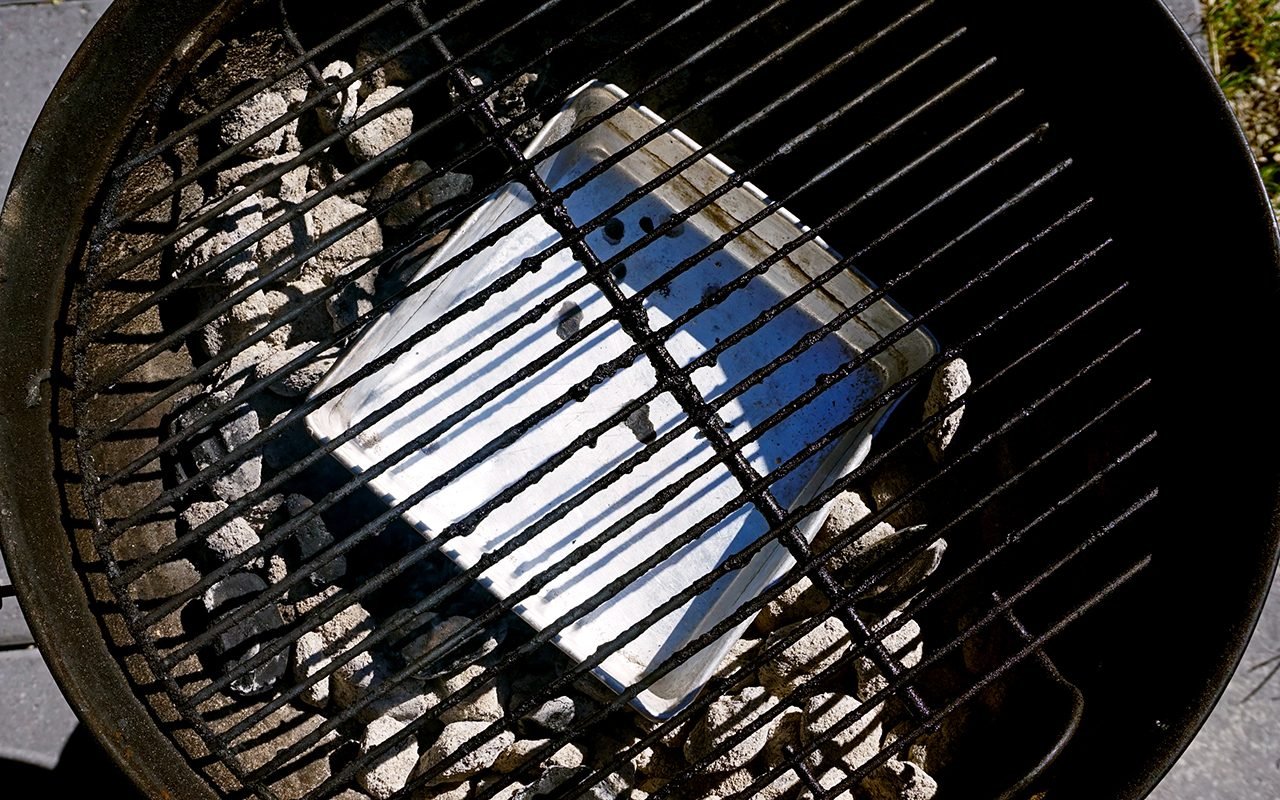 arranging the coals and drip pan for grilled thanksgiving turkey