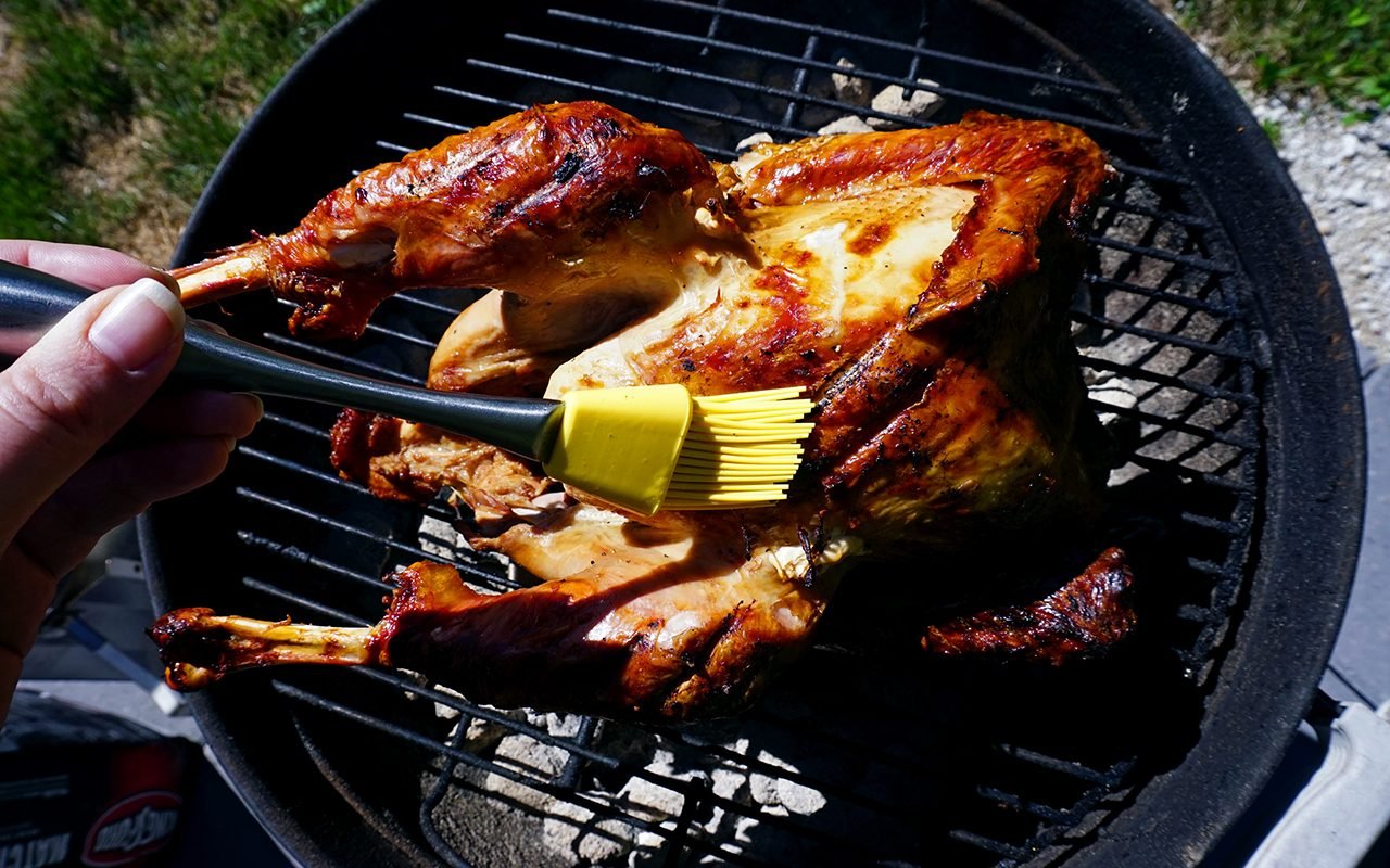 basting the grilled turkey with reserved marinde