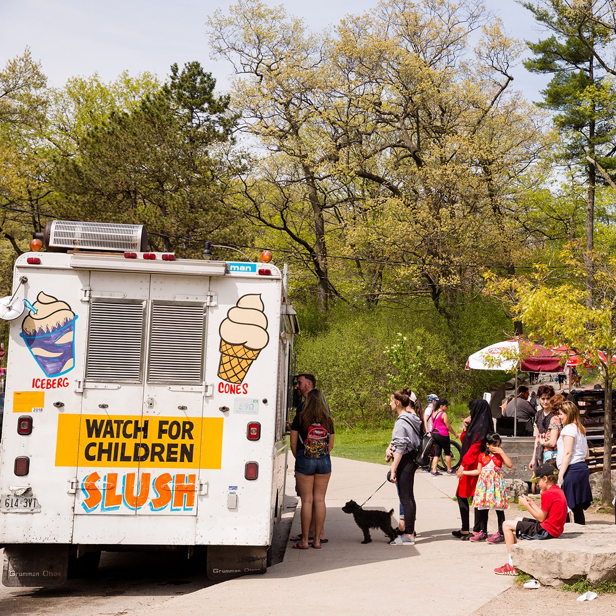 PEOPLE WAIT IN LONG LINE FOR ICE CREAM TRUCK AT HIGH PARK.