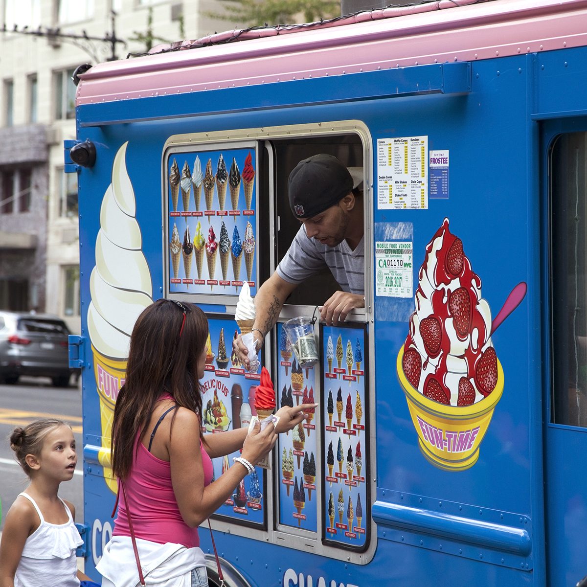 Man sells soft ice cream cone to customers on Columbus Circle. 