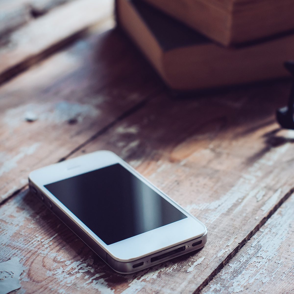 Old vintage books, smartphone and glasses on a wooden table