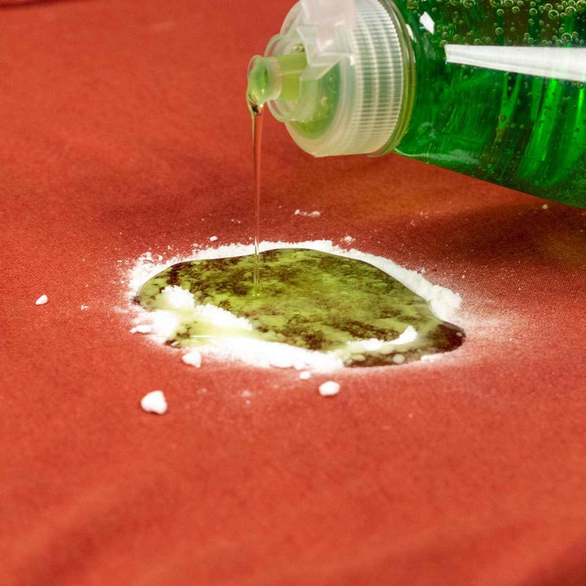 Pouring dish soap onto the baking soda covered stain