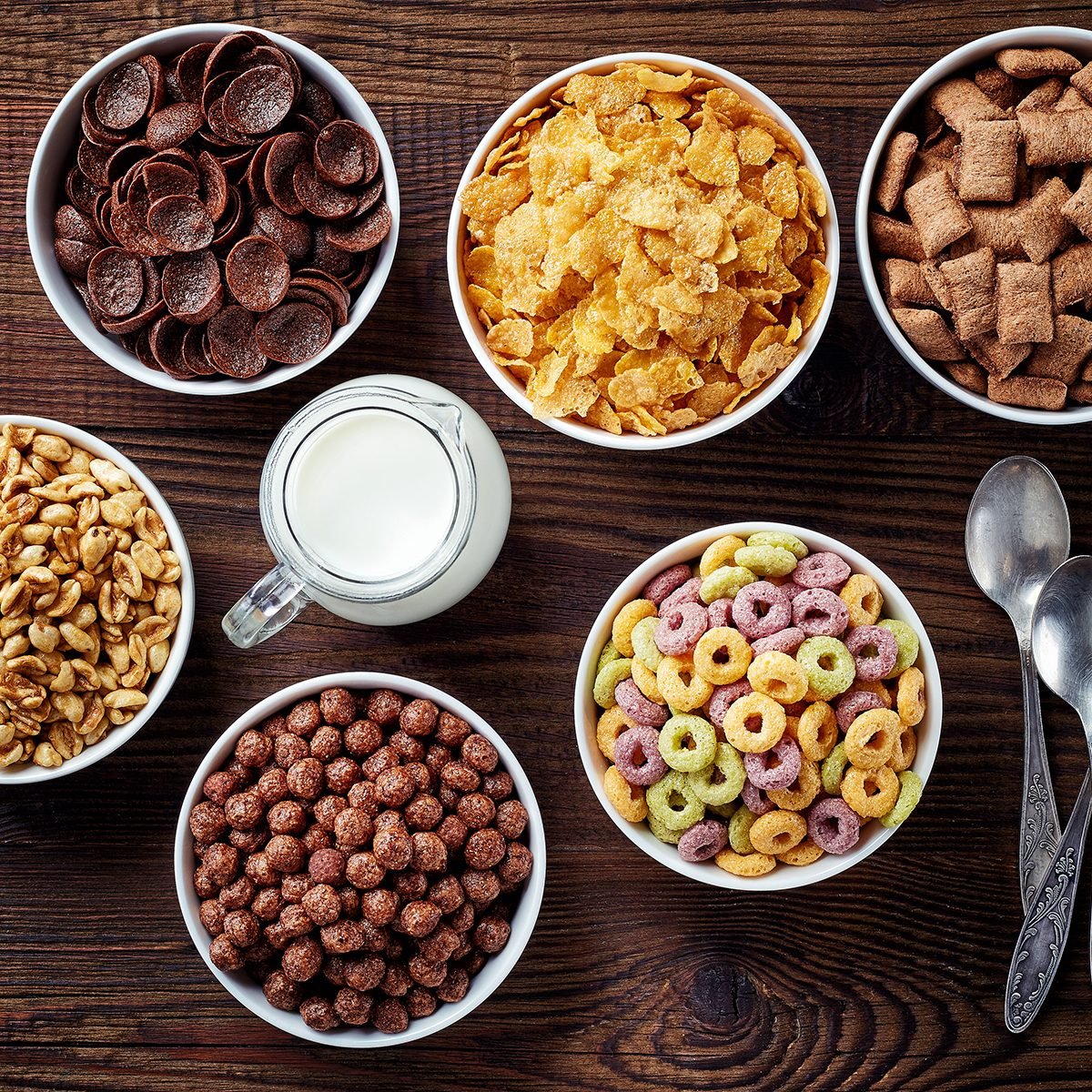 Bowls of various cereals and milk from top view