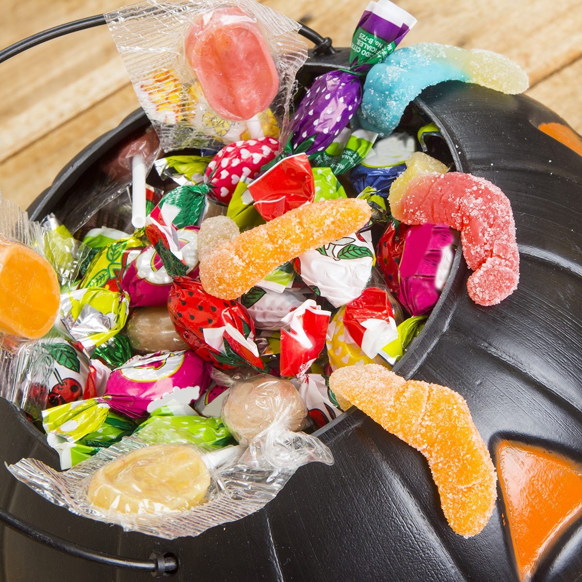 Black plastic pumpkin filled with candy wooden table