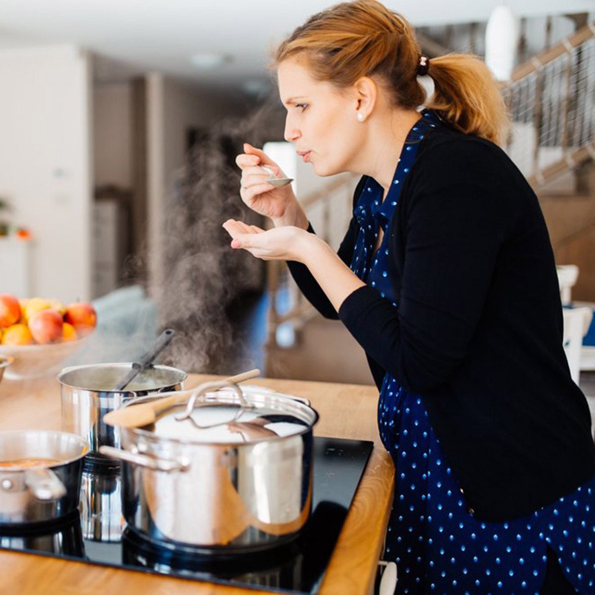 Woman tasting her food as she cooks