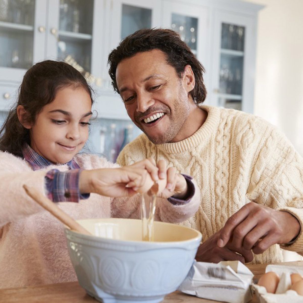 Family baking together adding eggs to a bowl