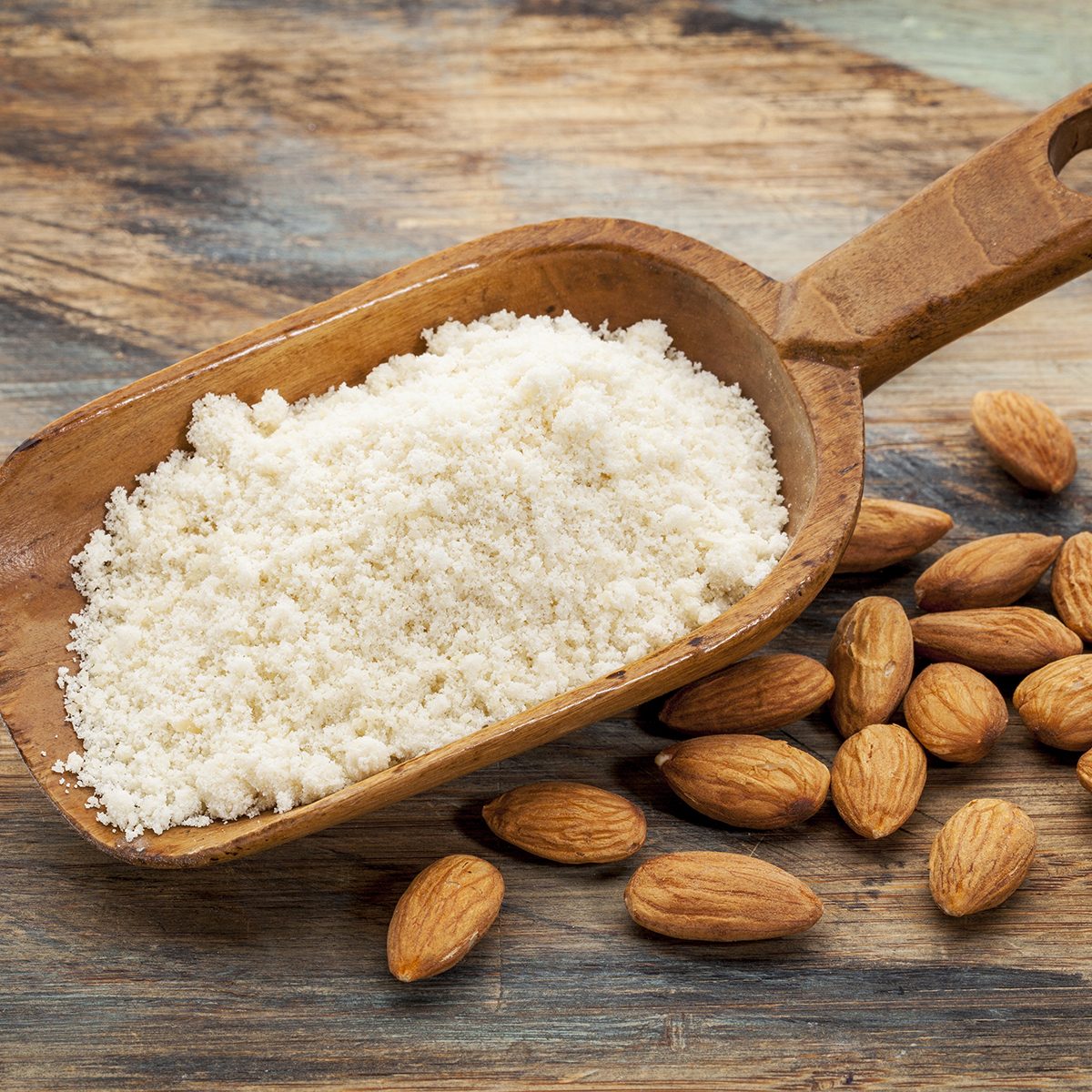 almond flour high in protein, low in carbohydrates, low in sugars and gluten free - a rustic wooden scoop on grained wood background