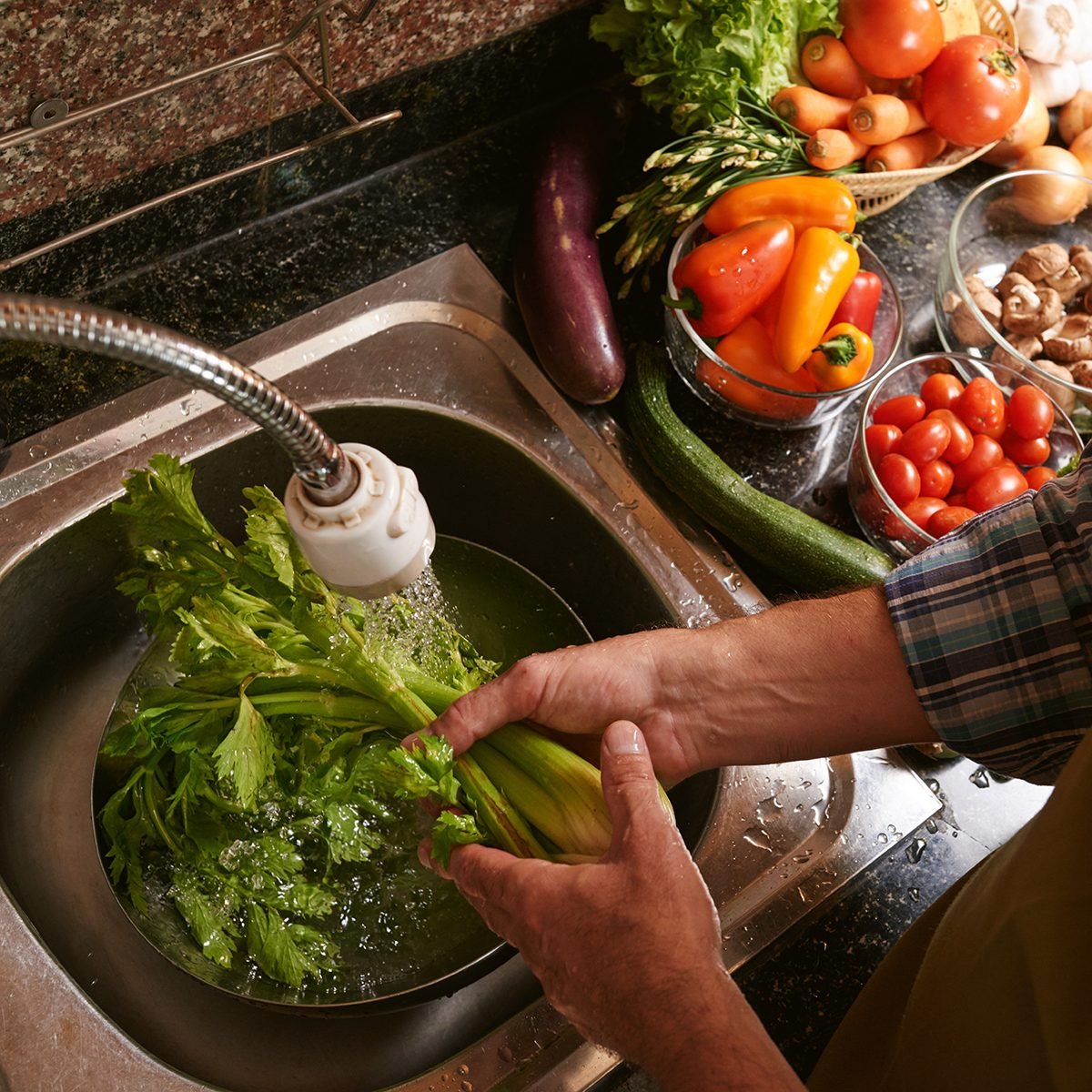 Man washing celery in the kitchen sink, view from above