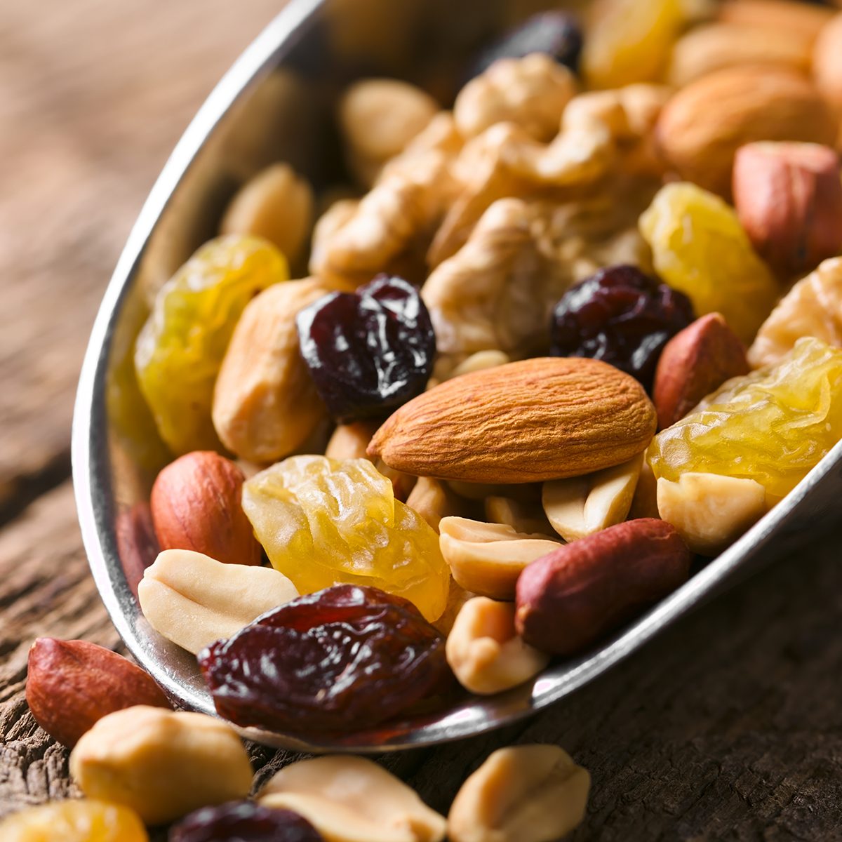 Healthy trail mix snack made of nuts (walnut, almond, peanut) and dried fruits (raisin, sultana) on iron scoop