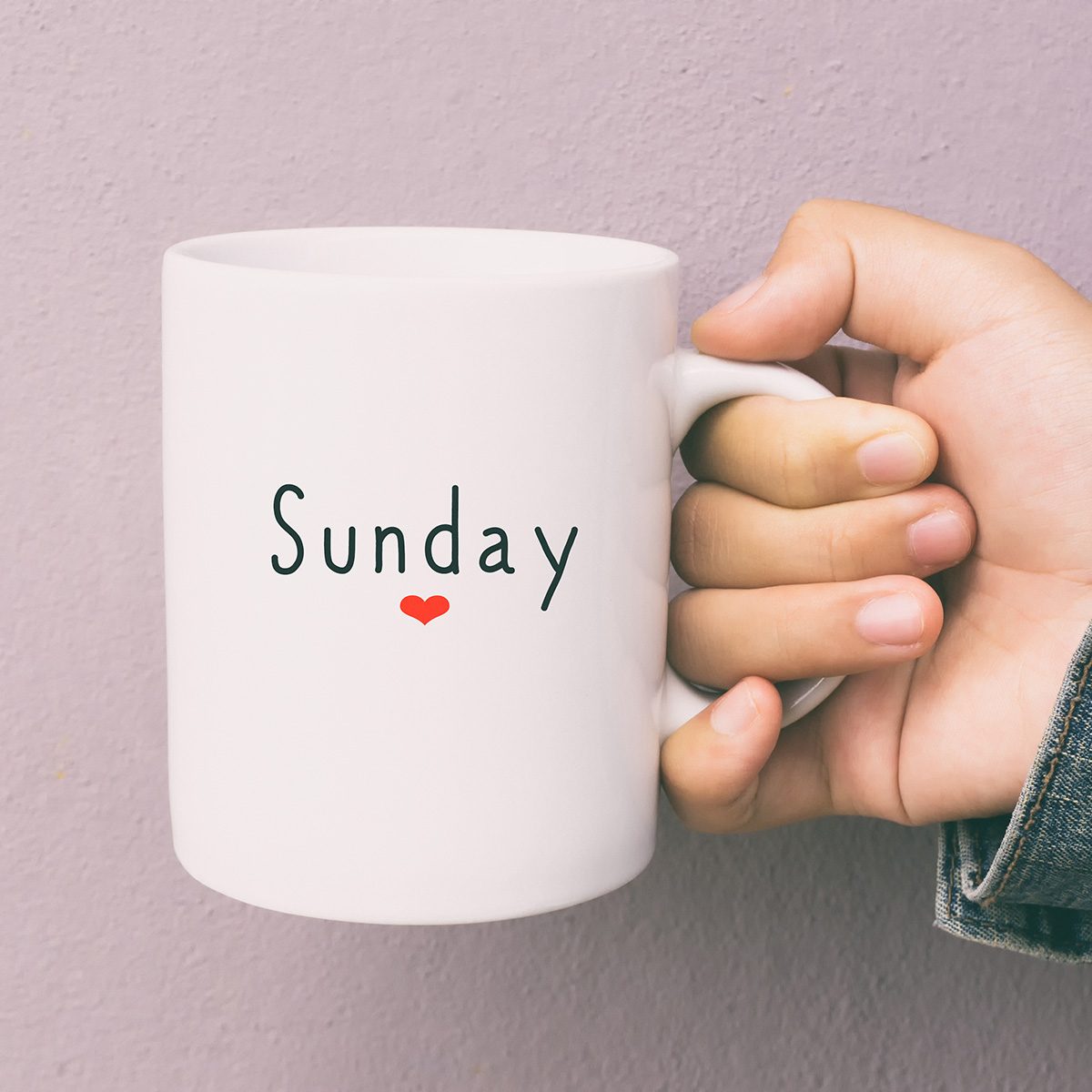 Woman Hand Holding a Cup of Coffee With Text Sunday.