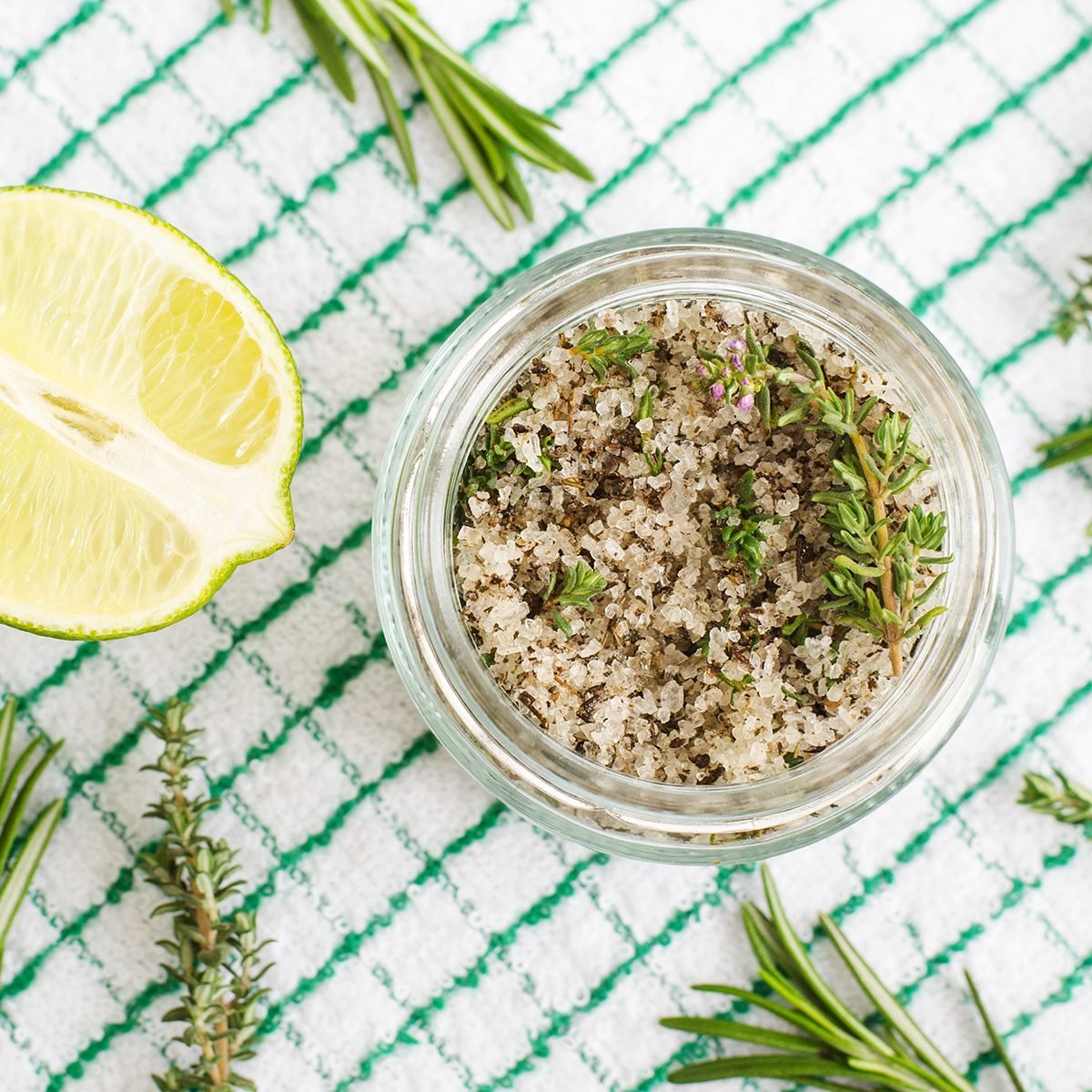 Homemade herbal scrub (foot soak or bath salt) with rosemary, thyme, lime juice, sea salt and olive oil. DIY beauty treatments and spa recipe. Top view, copy space