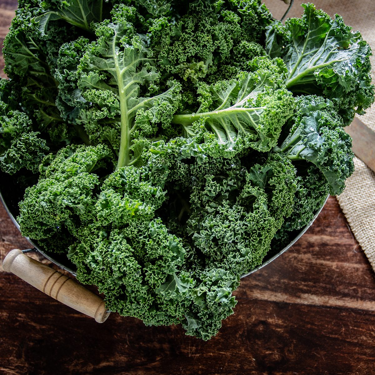 Green Kale in basket and knife on wooden background top view on daylight superfood vegetables Still life