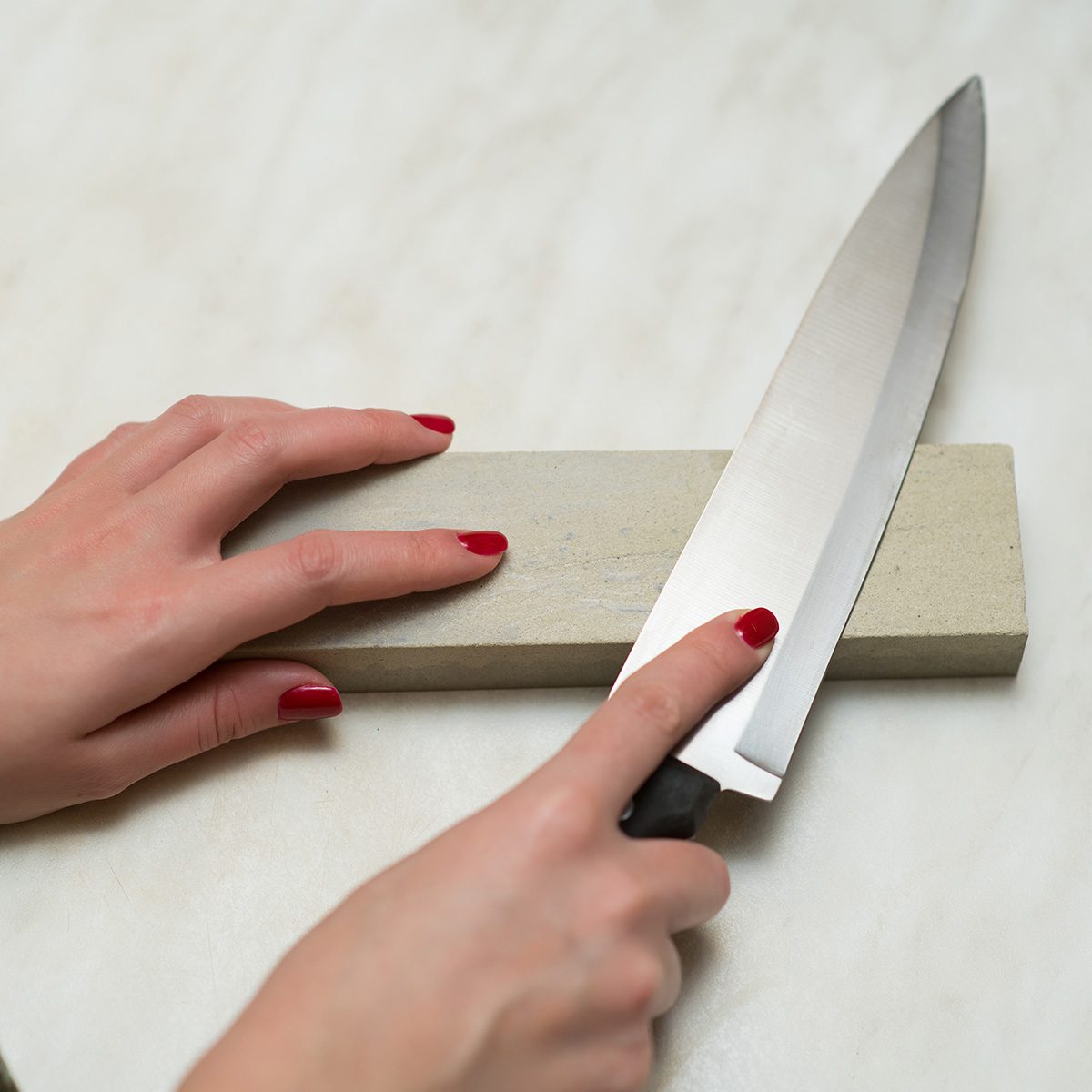 knife, whetstone and female hands. Woman and male work