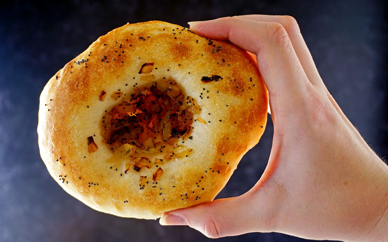 Frisch gebackene Bialy gefüllt mit karamellisierten Zwiebeln und Mohn