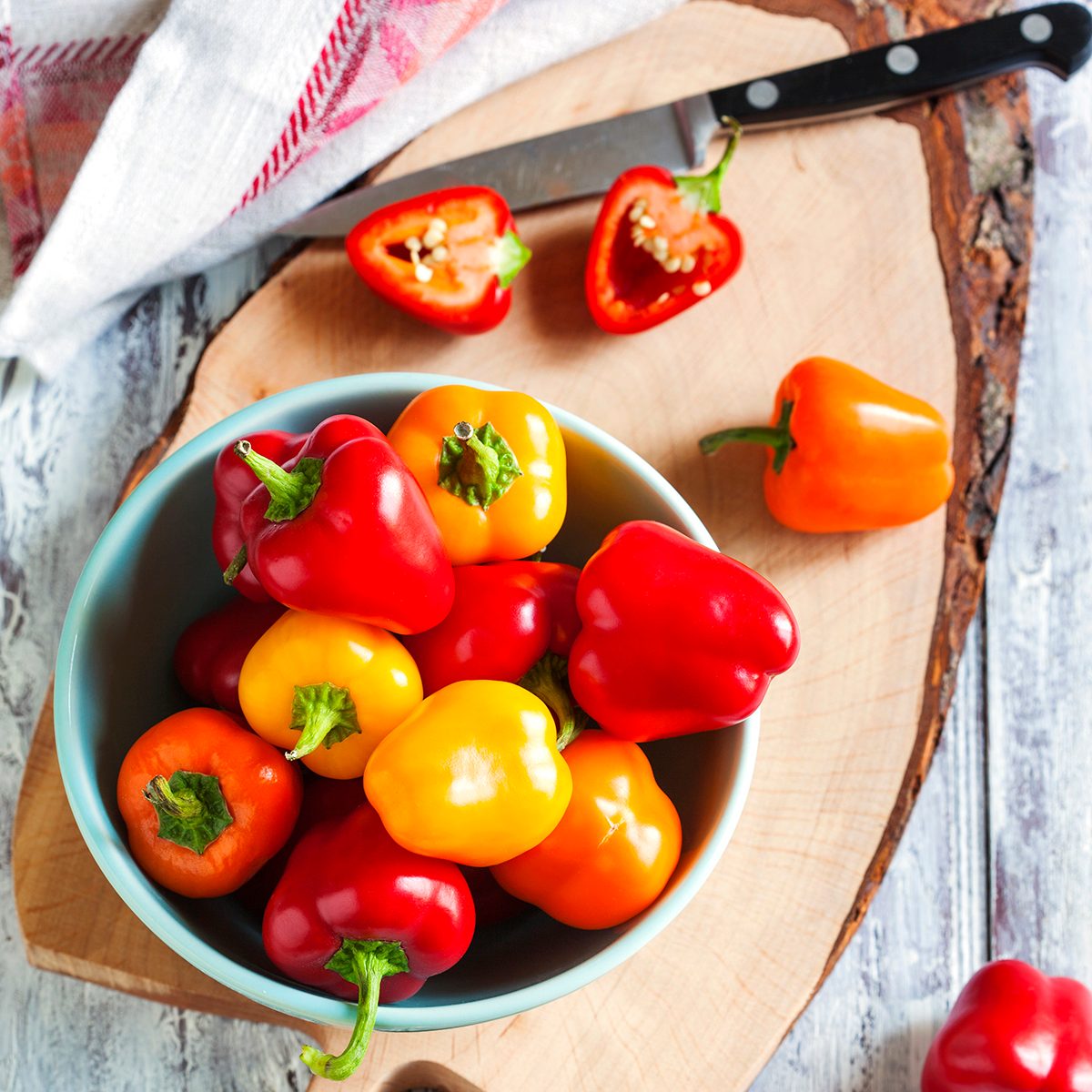 Mini bell peppers in bowl on wooden table. Top view.