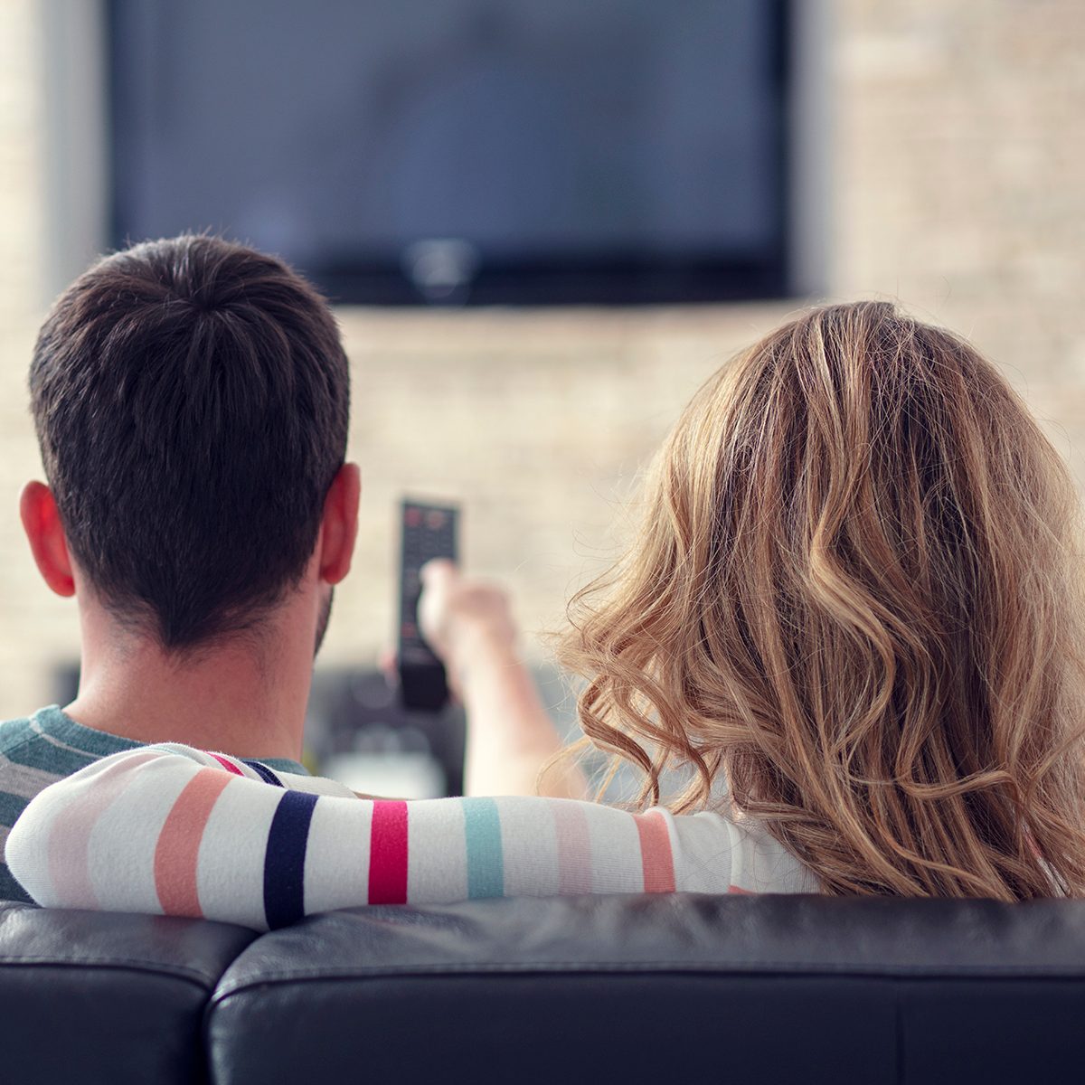 Happy young couple relaxing and watching TV at home