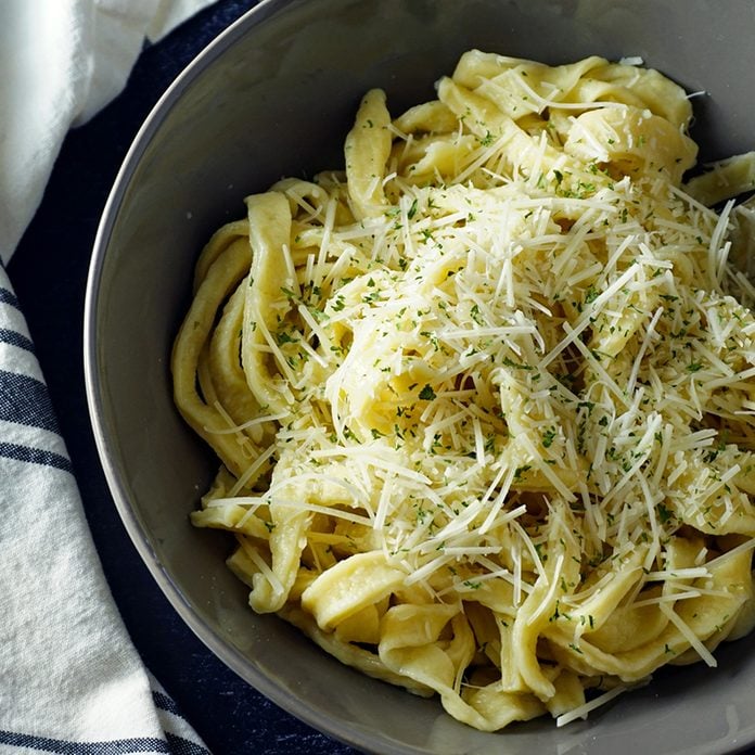 fresh, homemade egg noodles in a bowl topped with parmesan and butter