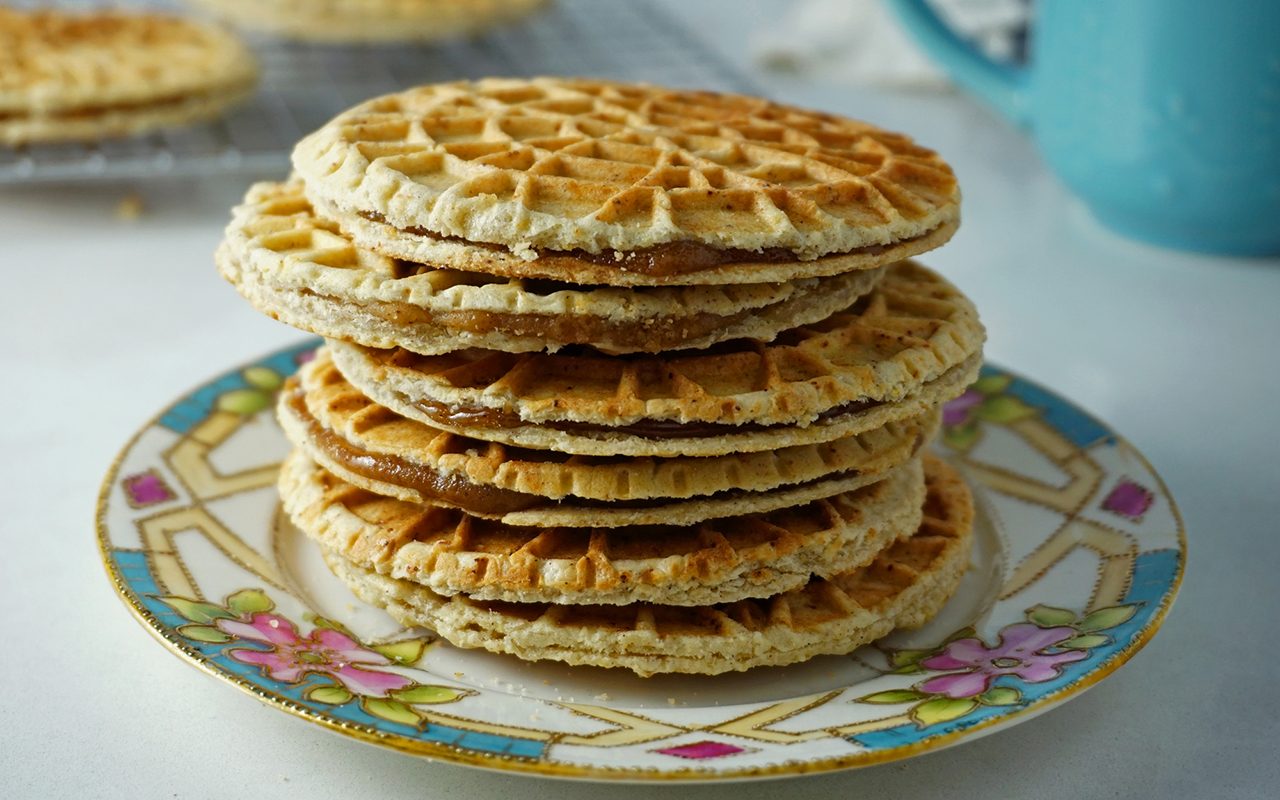 a stack of freshly made stroopwafels on a piece of china at an angle