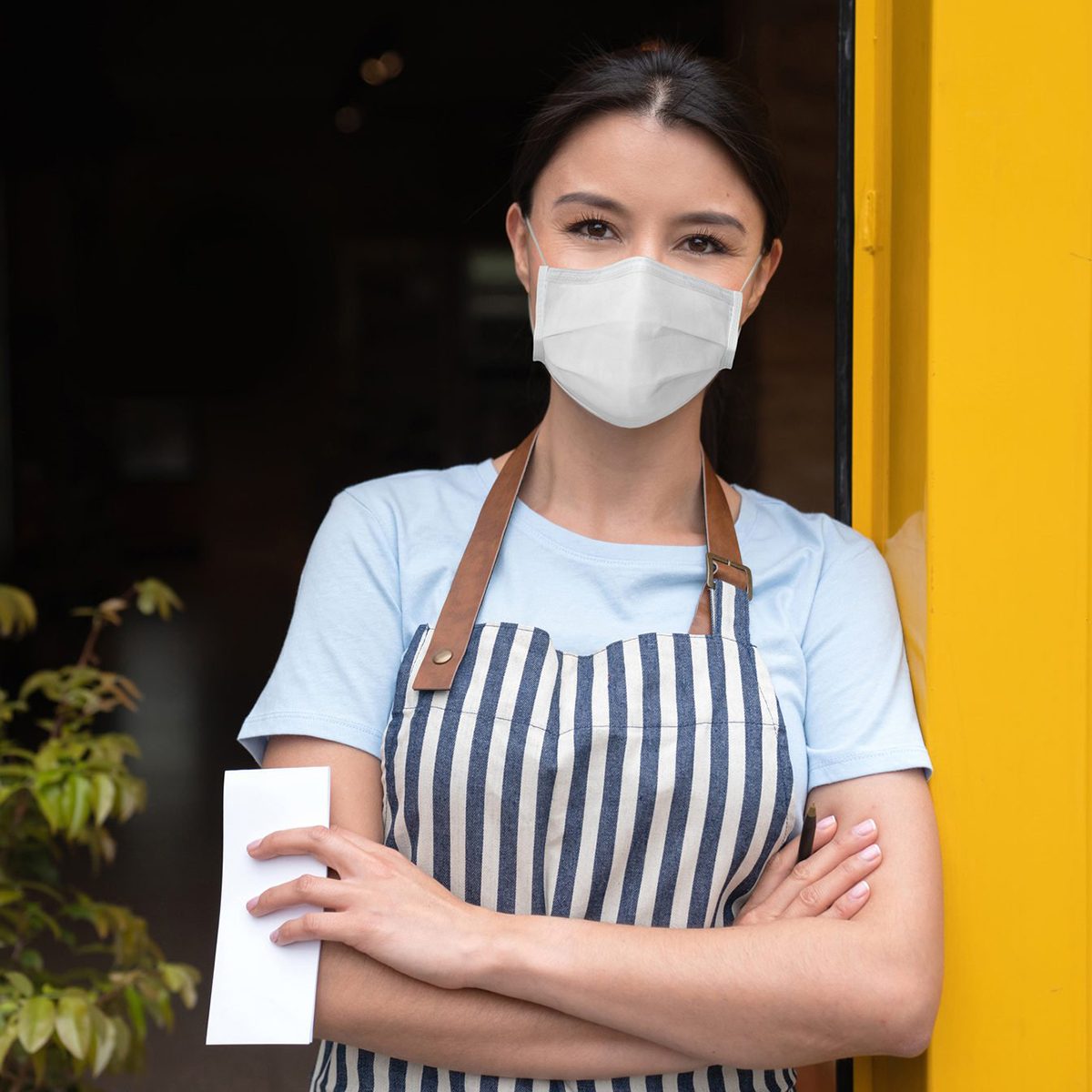 Business owner working at a cafe wearing a facemask