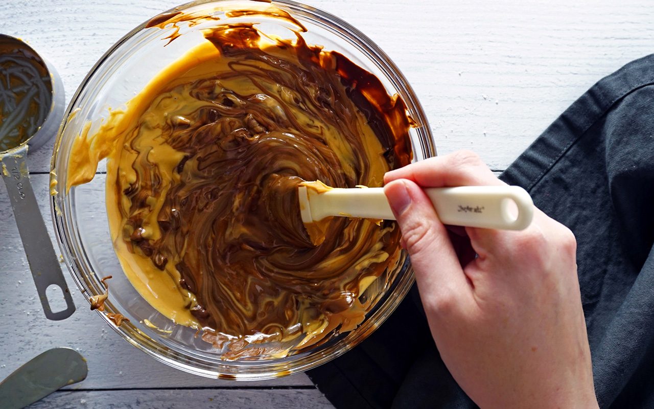 mixing melted chocolate and peanut butter together for homemade peanut butter cups