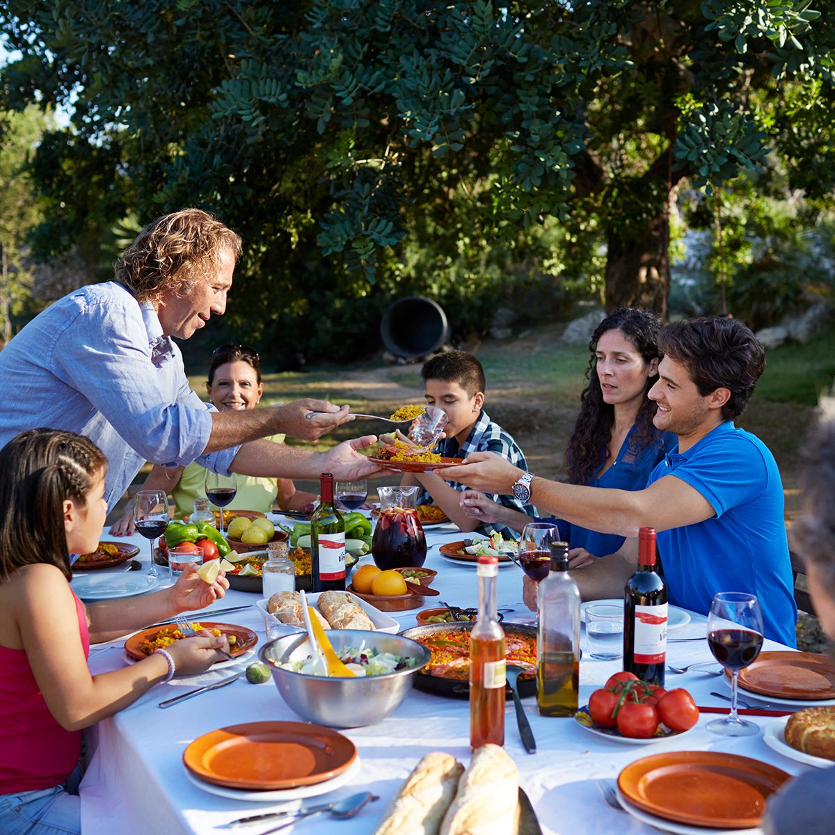 Multigenerational family together at dinner table at garden party in the sunset