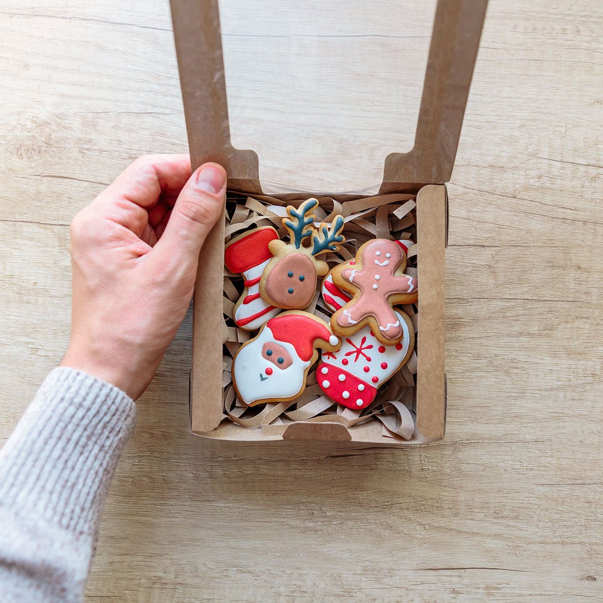 Opening Christmas present with Christmas cookies, personal perspective view