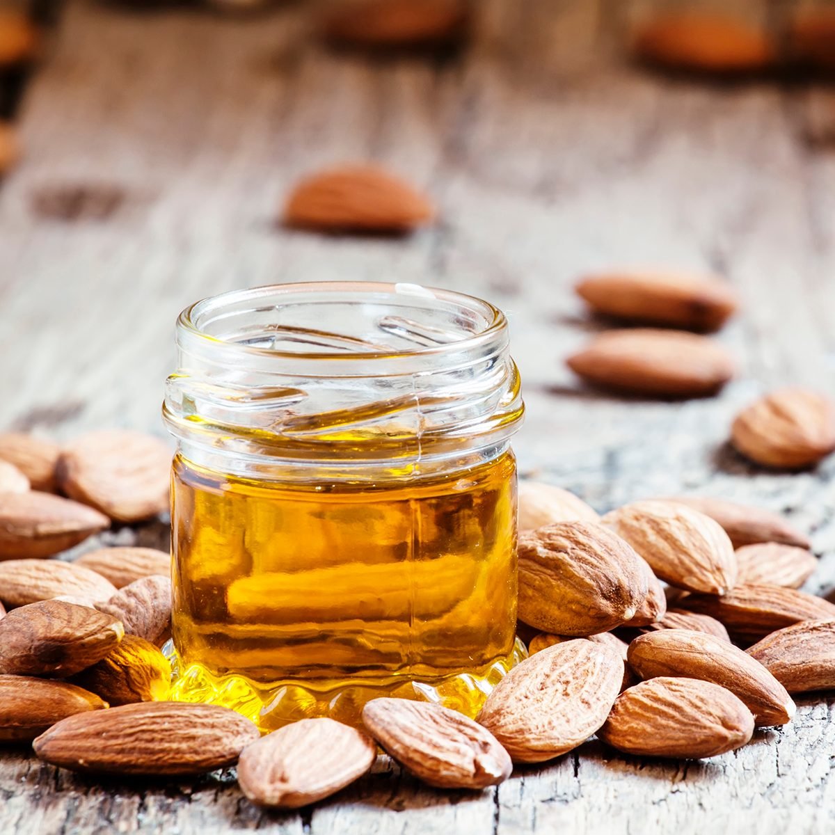 healthy oils Sweet Almond Oil, first extraction, in a small glass jar, dry almond nuts on an old wooden background, selective focus