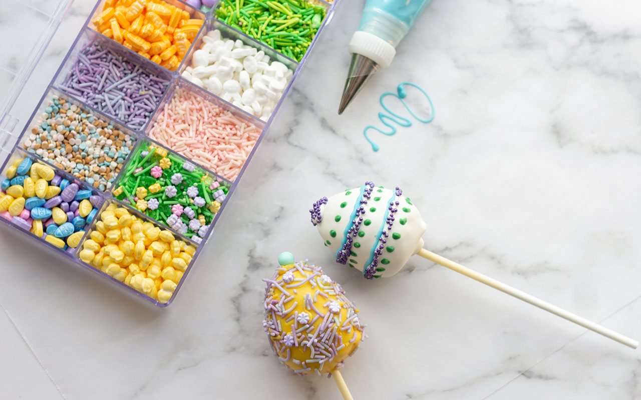 easter cake pops Box with sprinkles next to cake pops.