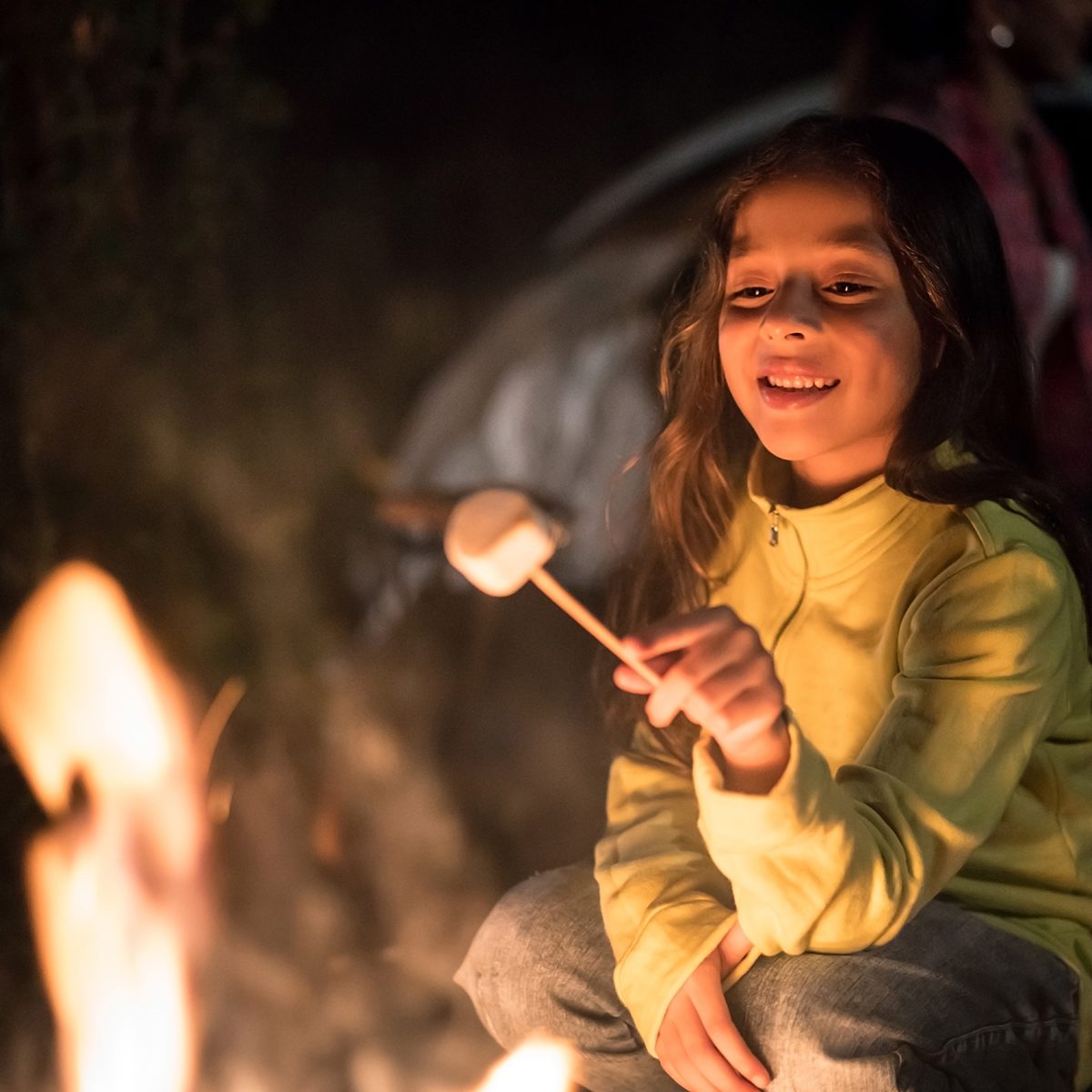 easter egg hunt ideas Portrait of a happy girl sitting outdoors by a bonfire eating marshmallows â outdoors lifestyle concepts