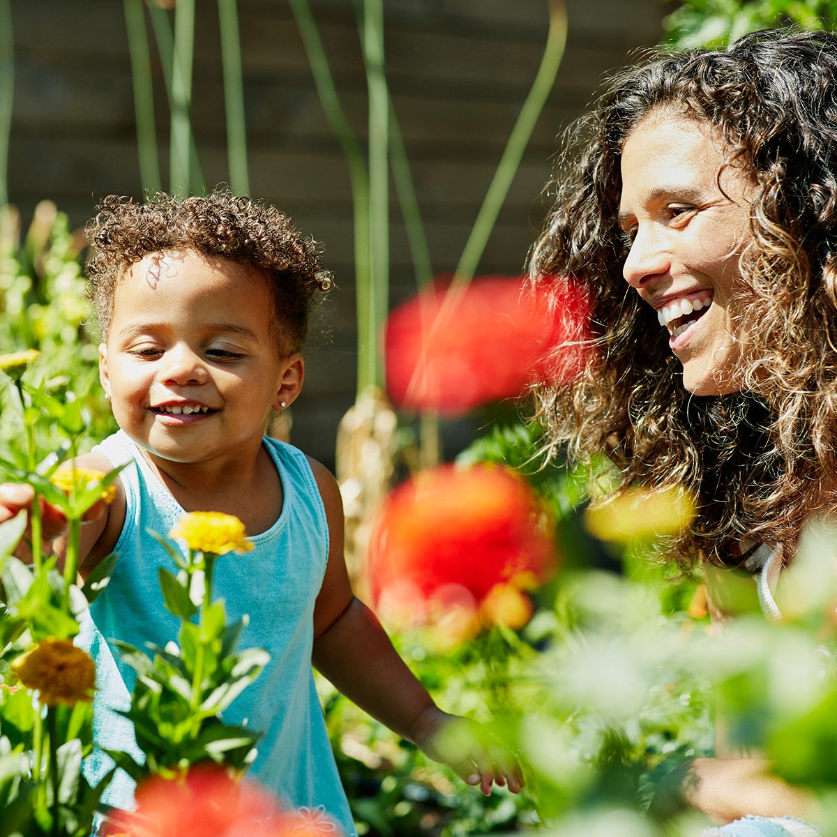 easter egg hunt ideas Smiling Mother And Toddler Daughter Enjoying Flowers Growing In Backyard Garden