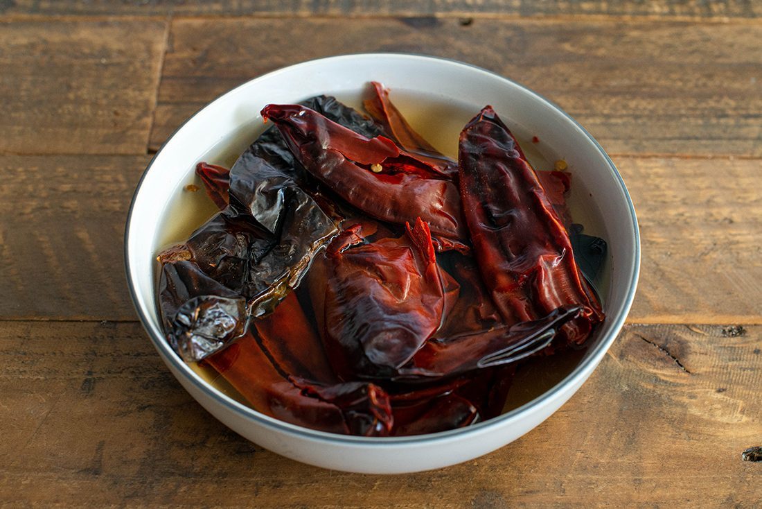 Chiles Soaking birria tacos