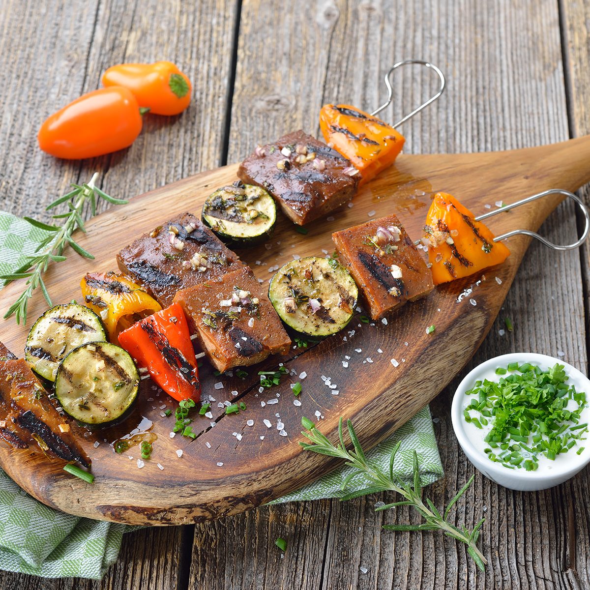 best meat substitutes Vegan meal: Grilled skewers with mixed vegetables and seitan served on a wooden cutting board with a herb soy sauce
