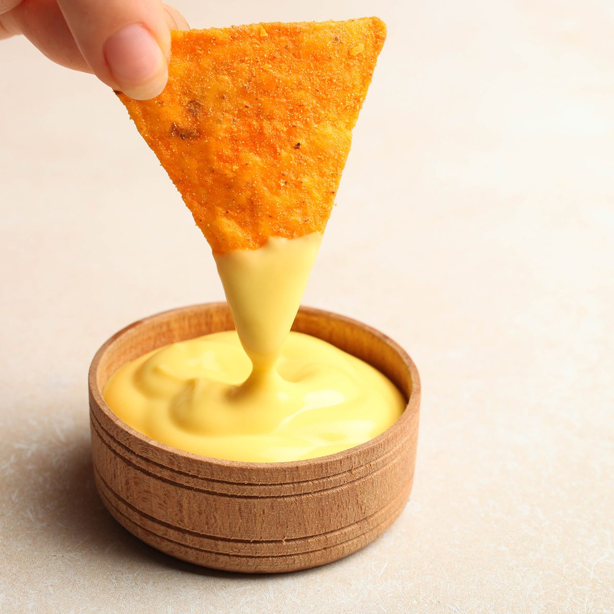Mexican crispy snack, nachos chips and cheese sauce on neutral background.