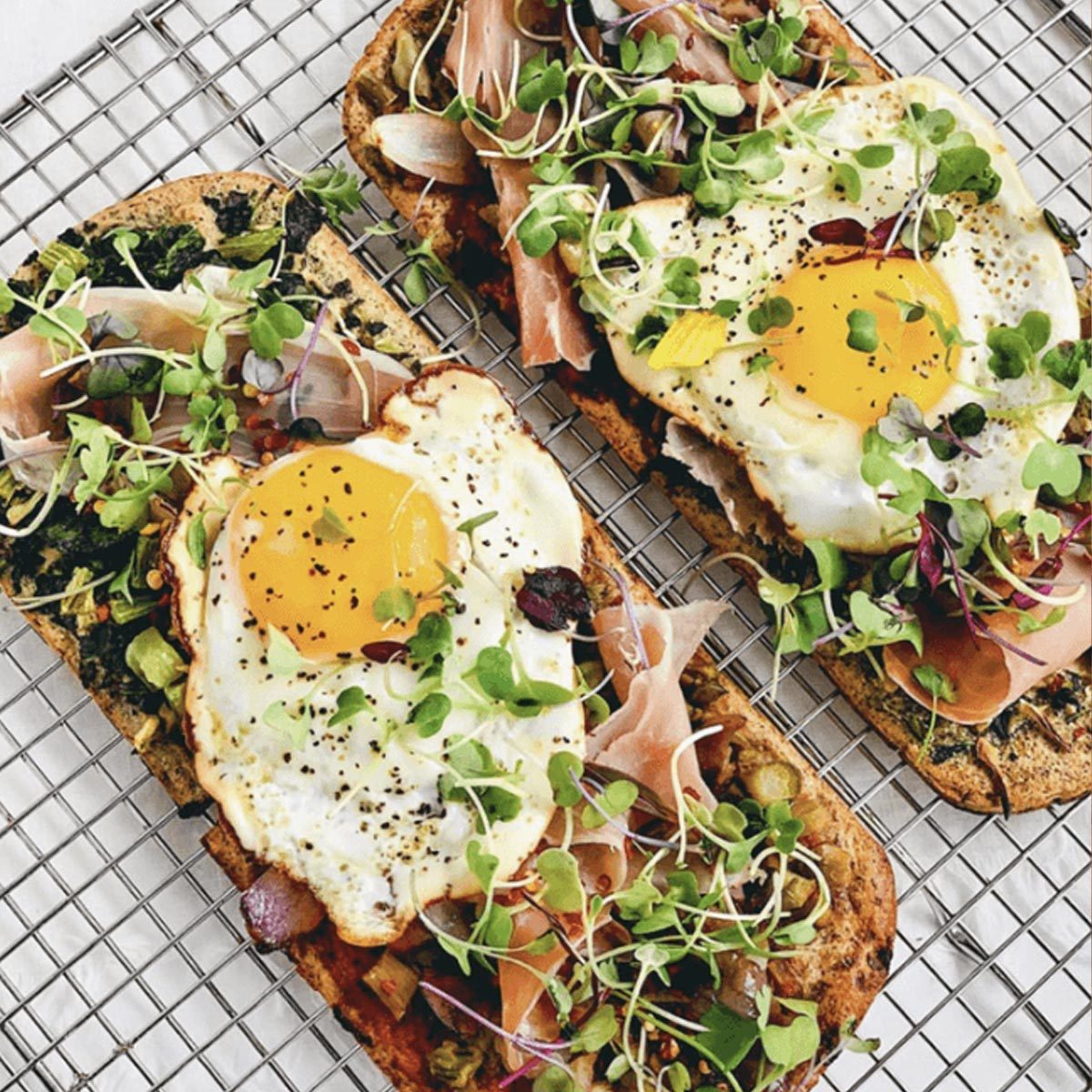 A Group of Toasts With Eggs and Vegetables on a Cooling Rack