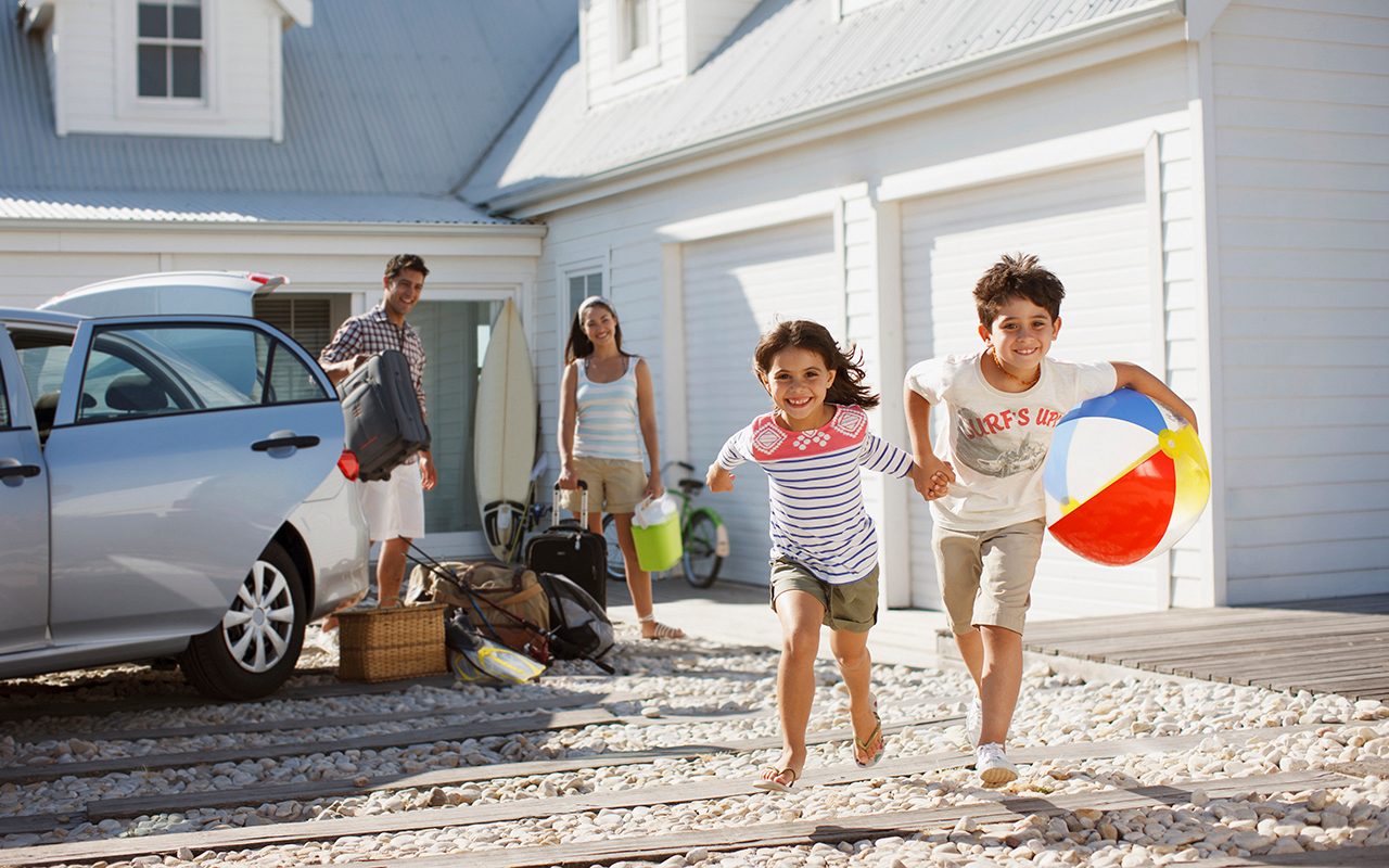 Brother And Sister With Beach Ball Running On Driveway