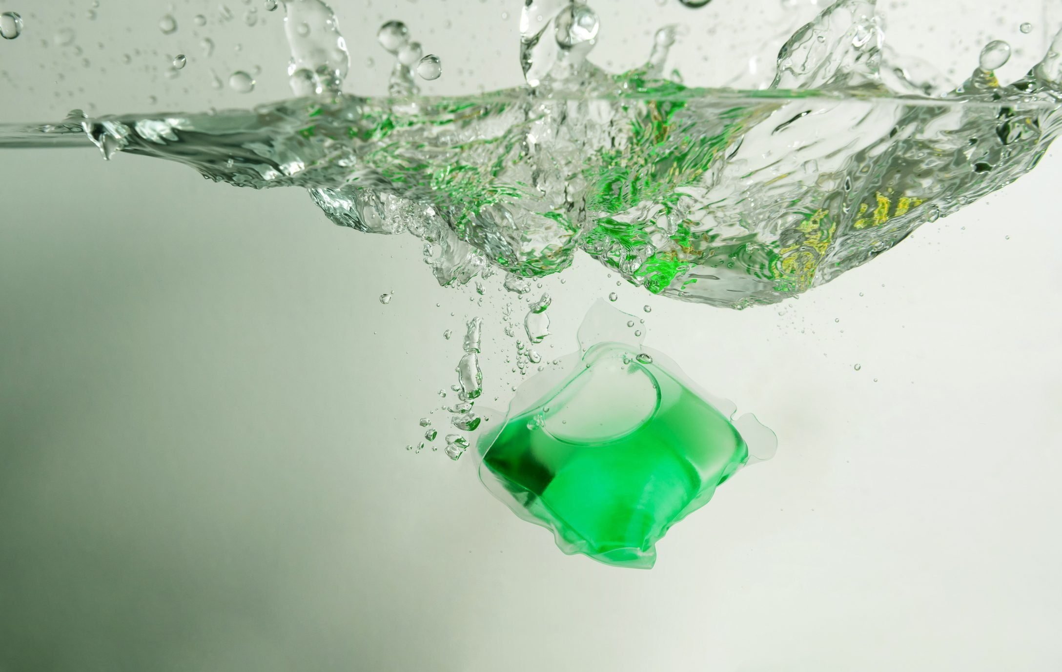 green laundry pod splashing into water